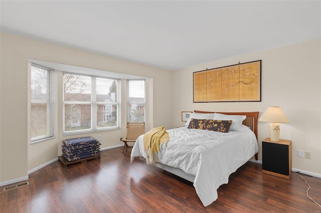 bedroom with baseboards, wood finished floors, and visible vents