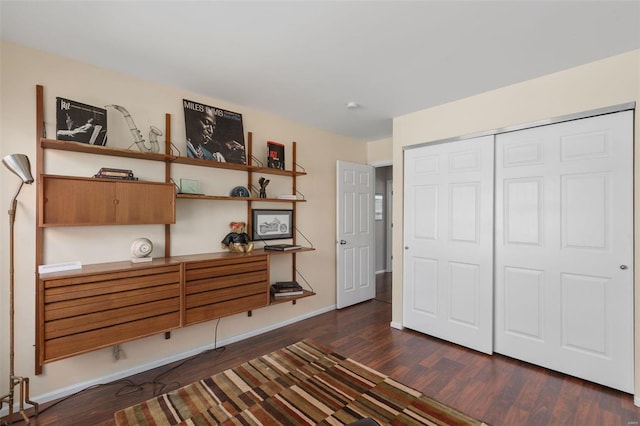 unfurnished bedroom featuring a closet, baseboards, and dark wood-type flooring