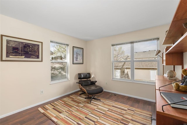 living area featuring baseboards, wood finished floors, and visible vents