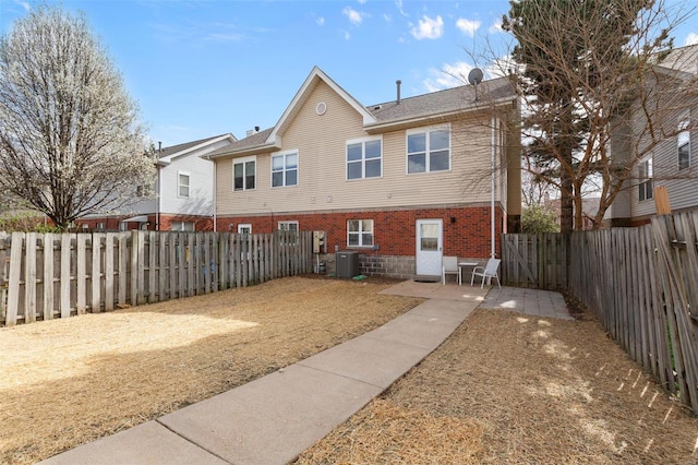 back of house featuring a fenced backyard, a patio, cooling unit, and brick siding