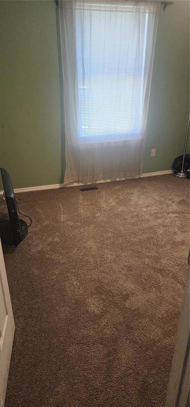 spare room with carpet floors, baseboards, and visible vents