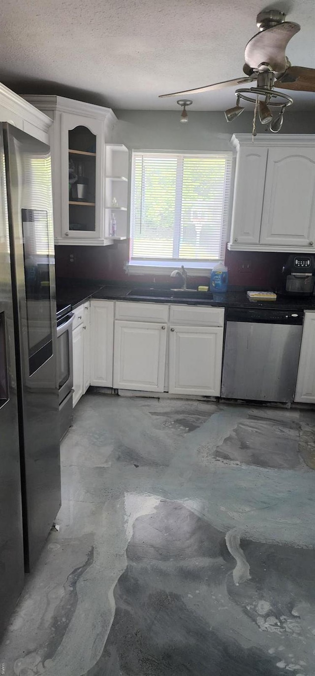 kitchen featuring dark countertops, white cabinets, appliances with stainless steel finishes, and a sink