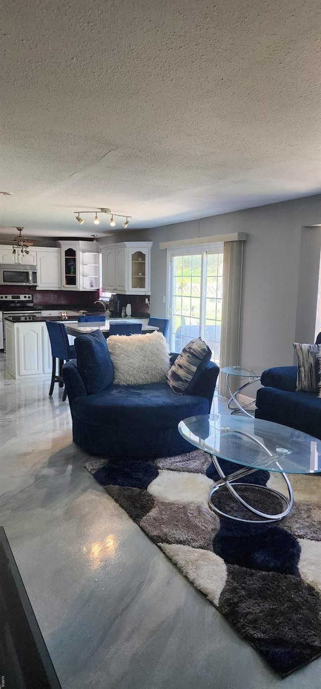 living area with track lighting, a textured ceiling, and finished concrete flooring