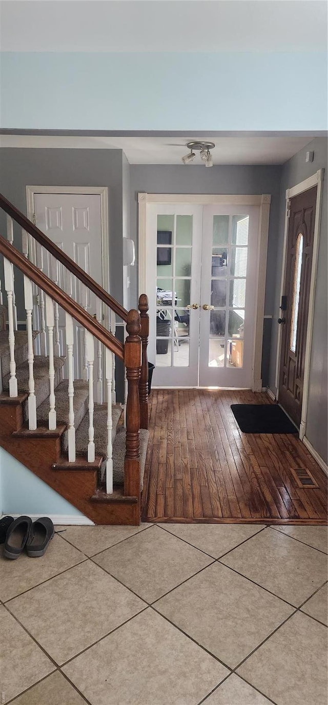 entrance foyer with tile patterned flooring, french doors, baseboards, and stairs
