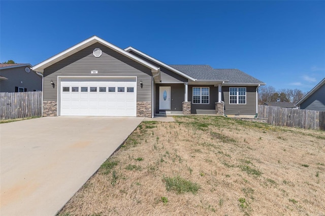 view of front of house featuring stone siding, an attached garage, fence, and concrete driveway