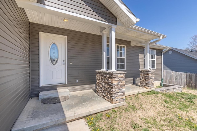 view of exterior entry with covered porch and fence