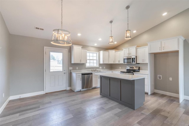 kitchen with light wood-type flooring, light countertops, appliances with stainless steel finishes, and visible vents