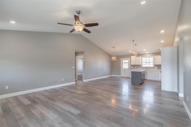 unfurnished living room featuring baseboards, a sink, a ceiling fan, and wood finished floors
