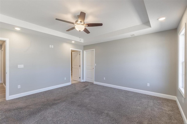 carpeted spare room featuring a raised ceiling, recessed lighting, baseboards, and ceiling fan