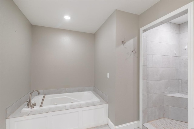 bathroom featuring a tub with jets, baseboards, and tiled shower
