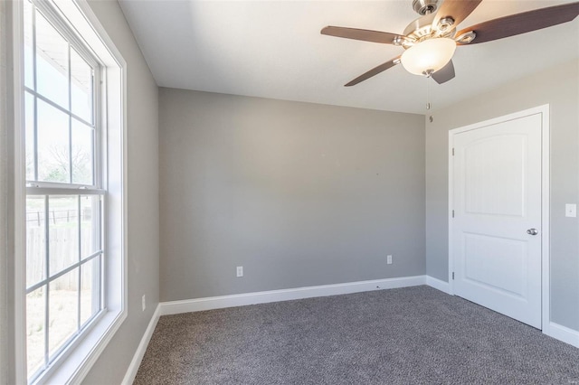 carpeted spare room with baseboards, a healthy amount of sunlight, and a ceiling fan