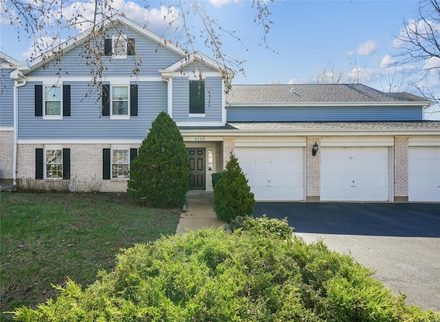 view of front of house with aphalt driveway, a garage, brick siding, and a front yard