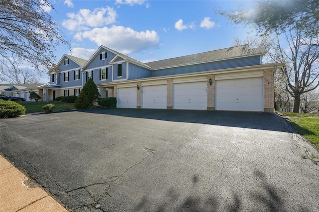 view of front facade featuring aphalt driveway, brick siding, and a garage