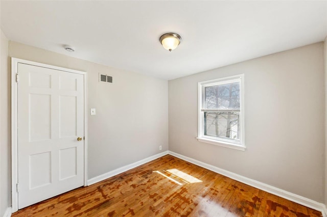 empty room with baseboards, visible vents, and wood finished floors
