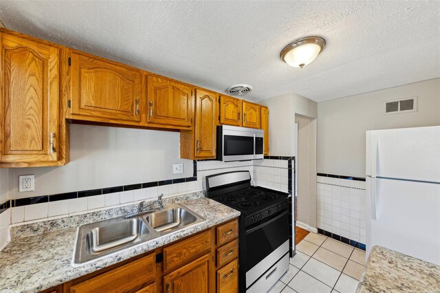 kitchen with stainless steel microwave, gas range oven, freestanding refrigerator, and visible vents