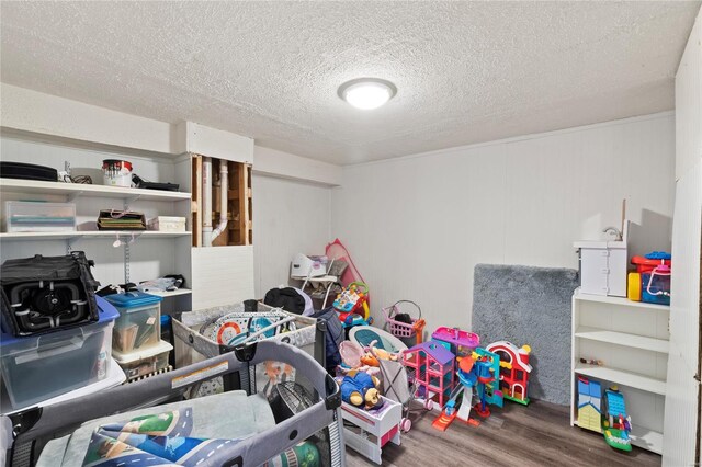 game room with a textured ceiling and wood finished floors