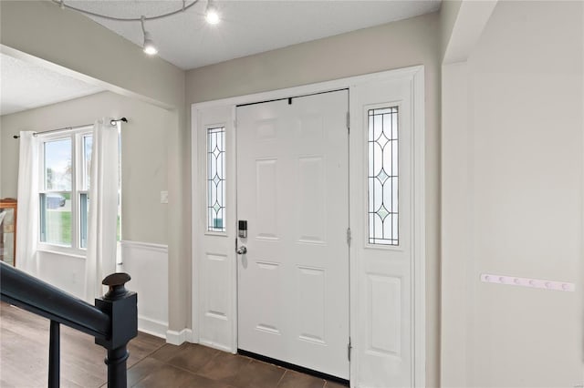 entrance foyer with baseboards, rail lighting, and a textured ceiling