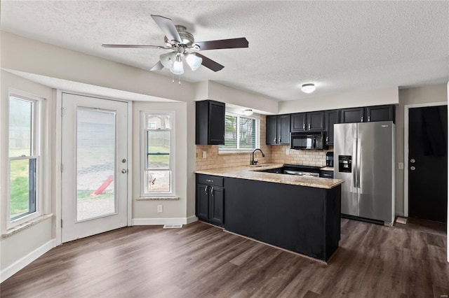 kitchen featuring stainless steel fridge, tasteful backsplash, dark wood-style floors, a peninsula, and black microwave