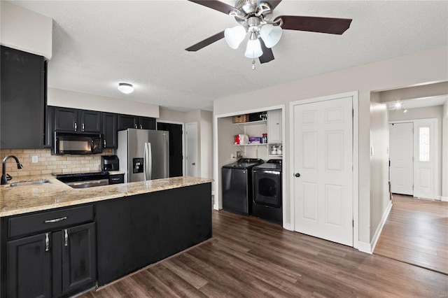 kitchen featuring a sink, black microwave, washing machine and clothes dryer, stainless steel fridge, and dark wood-style floors