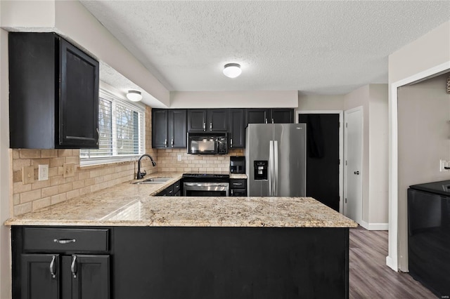 kitchen with tasteful backsplash, dark wood-style flooring, stainless steel appliances, a sink, and a peninsula