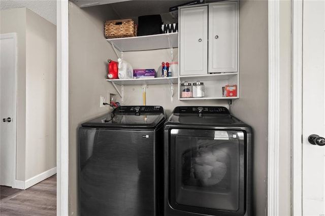 laundry room with wet bar, wood finished floors, baseboards, independent washer and dryer, and cabinet space
