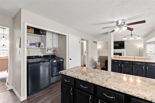 kitchen featuring a fireplace, ceiling fan, independent washer and dryer, and dark cabinetry