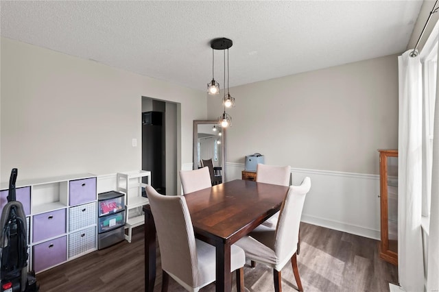 dining space with dark wood-style flooring and a textured ceiling