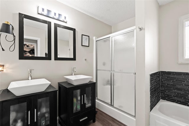bathroom with a sink, a textured ceiling, and a shower stall