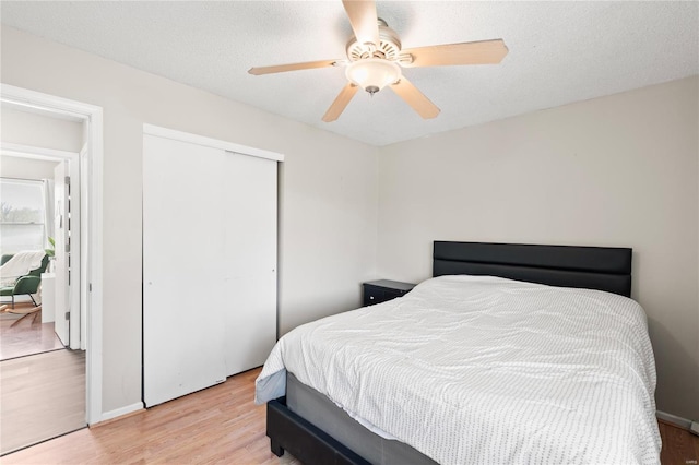bedroom with a closet, a textured ceiling, ceiling fan, and light wood finished floors
