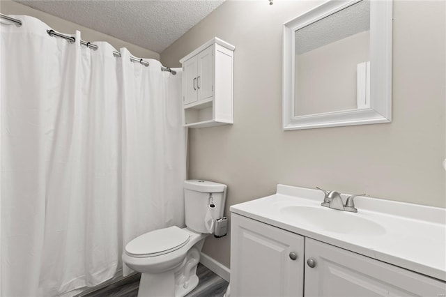 bathroom with toilet, vanity, wood finished floors, and a textured ceiling