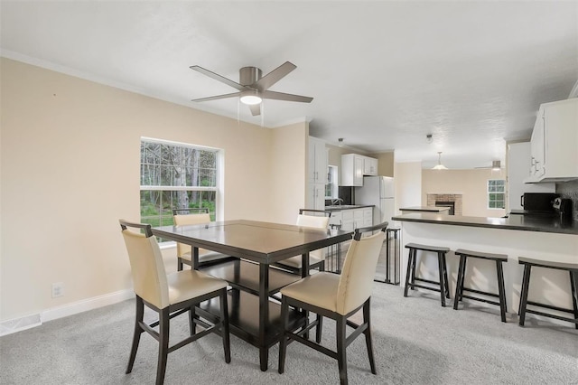 dining space featuring light carpet, a ceiling fan, visible vents, and baseboards