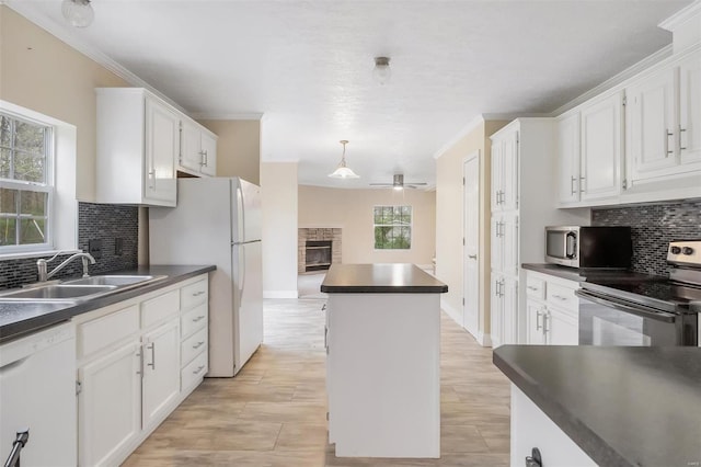 kitchen featuring a sink, tasteful backsplash, dark countertops, white appliances, and a stone fireplace