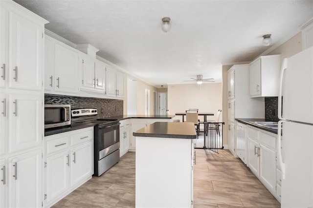 kitchen with a peninsula, white cabinetry, backsplash, and appliances with stainless steel finishes