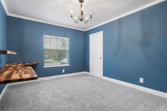 carpeted spare room featuring crown molding, baseboards, a notable chandelier, and a textured ceiling
