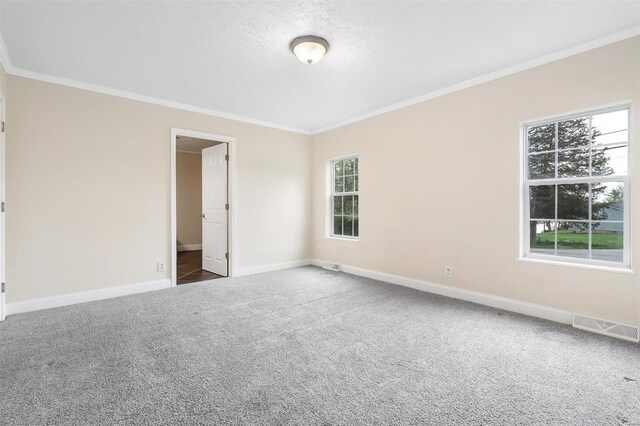 empty room with a textured ceiling, visible vents, baseboards, carpet floors, and ornamental molding