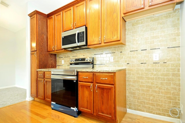 kitchen featuring baseboards, appliances with stainless steel finishes, light wood finished floors, and visible vents