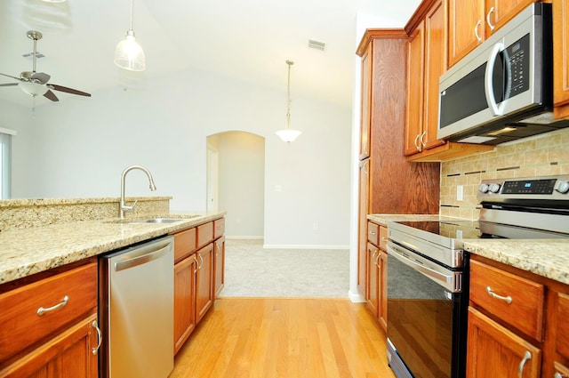 kitchen featuring visible vents, a sink, arched walkways, decorative backsplash, and appliances with stainless steel finishes