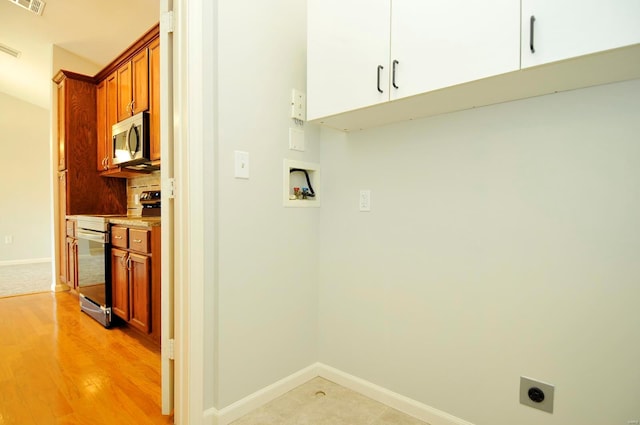 washroom featuring hookup for an electric dryer, baseboards, visible vents, hookup for a washing machine, and cabinet space