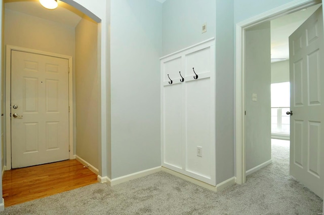 mudroom featuring arched walkways, baseboards, and carpet floors