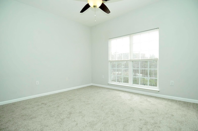 carpeted spare room featuring baseboards and ceiling fan