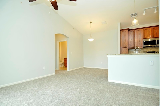 kitchen featuring stainless steel microwave, visible vents, backsplash, light colored carpet, and ceiling fan