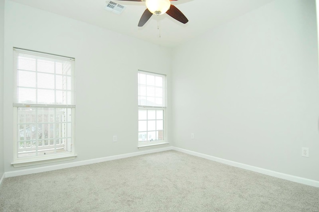 carpeted empty room with baseboards, visible vents, and ceiling fan