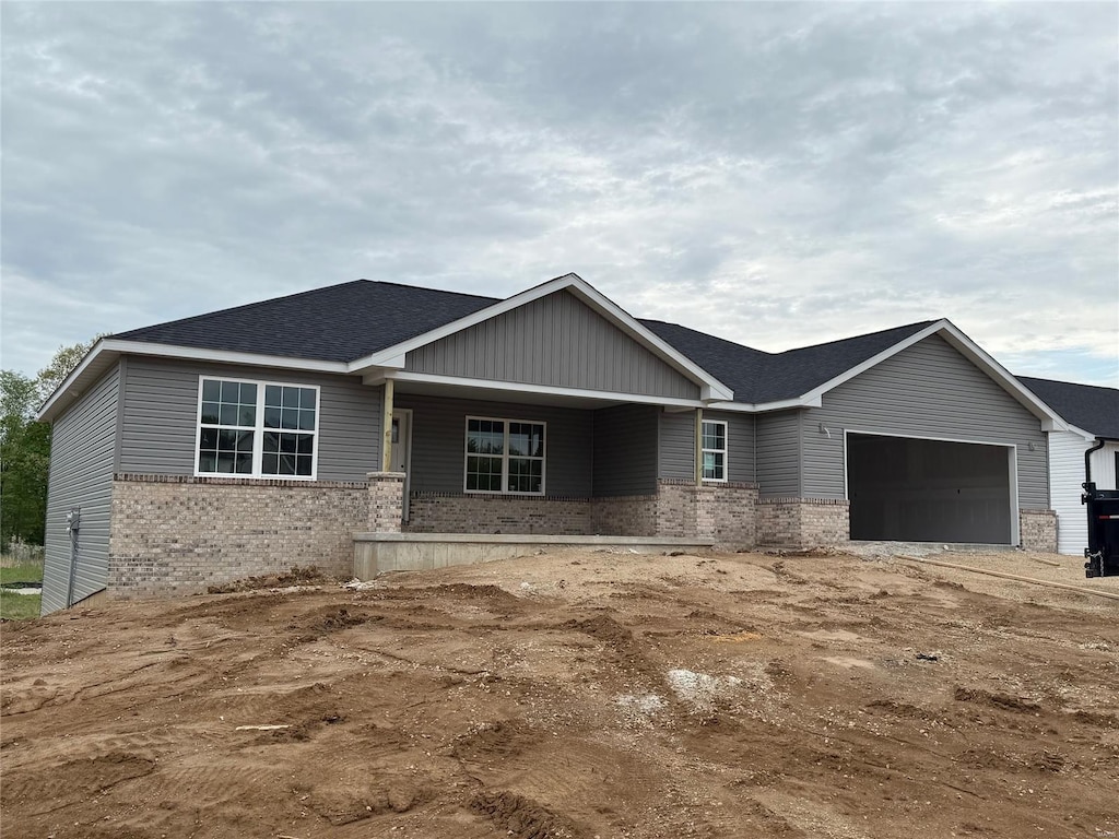 view of front of property with roof with shingles, brick siding, and a garage
