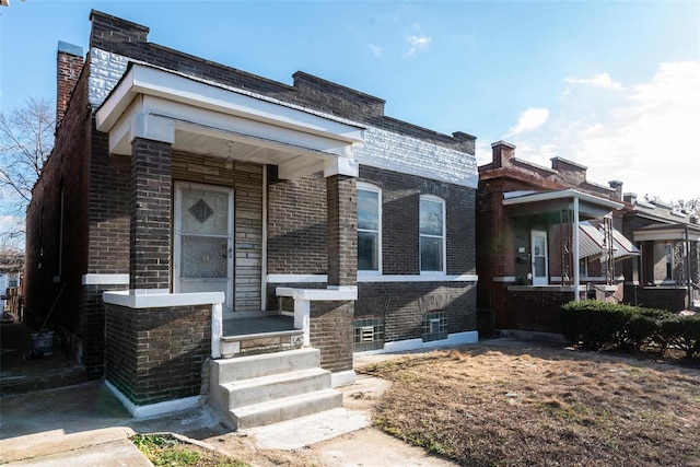 view of front facade with brick siding and a chimney