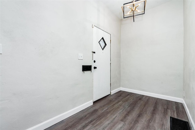 foyer entrance featuring dark wood-type flooring, a notable chandelier, baseboards, and visible vents