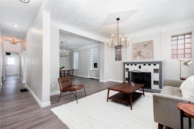 living room featuring a notable chandelier, wood finished floors, visible vents, and baseboards