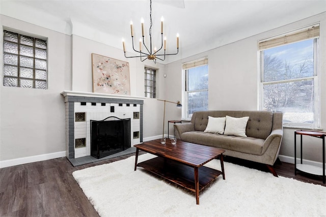 living area with a fireplace, an inviting chandelier, wood finished floors, and baseboards
