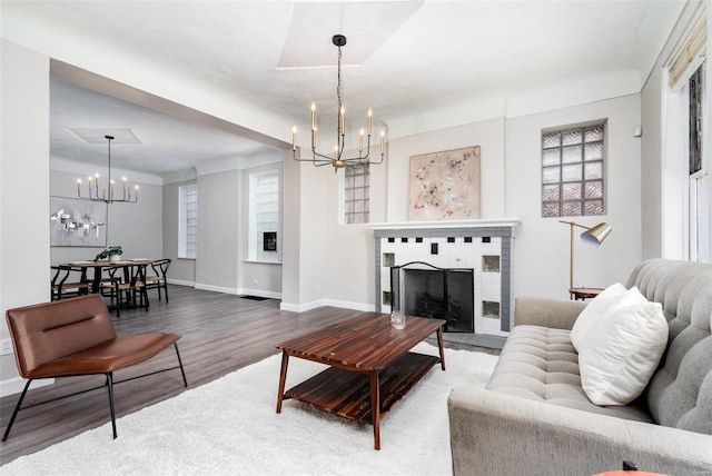 living area featuring baseboards, an inviting chandelier, wood finished floors, and a fireplace