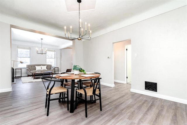 dining area with a notable chandelier, wood finished floors, visible vents, and baseboards