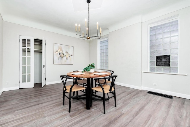 dining area with visible vents, baseboards, a notable chandelier, and wood finished floors